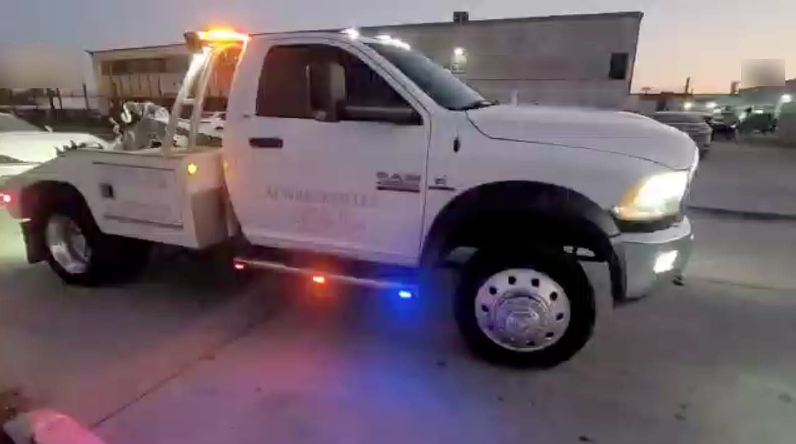 Una grúa de levante de ruedas de A1 Wrecker al anochecer, vista de lado, con sus luces ámbar y azules encendidas